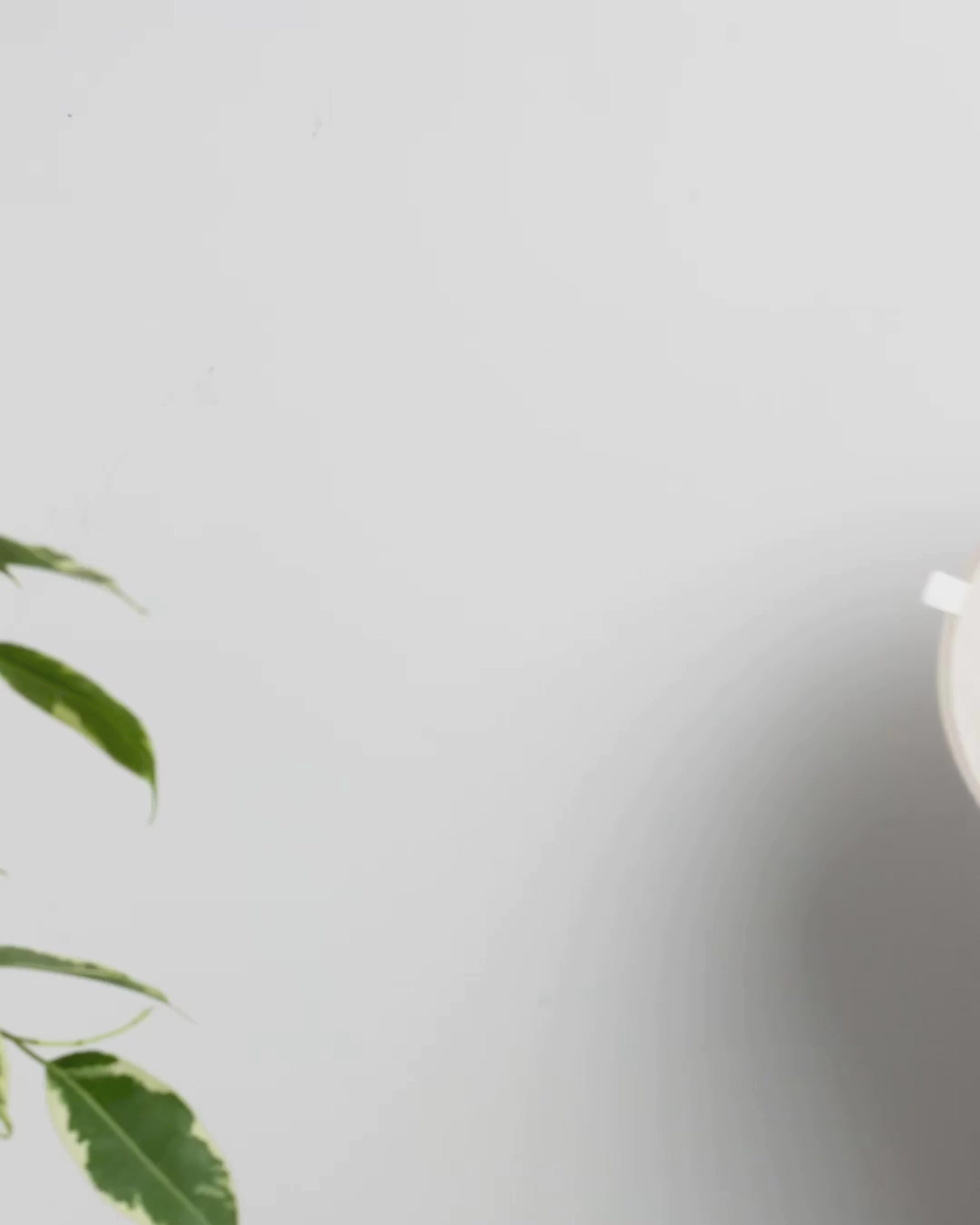 Close-up of a hand peeling a clear plastic protective film from the back of a soft-brown, arch-shaped silicone shower caddy to reveal its adhesive surface. The video demonstrates the easy, tool-free, peel-and-stick mounting process.